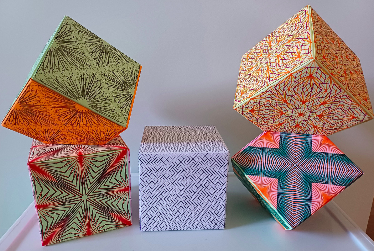 Various Jackson Cubes, folded with paper, decorated with pen plotted patterns